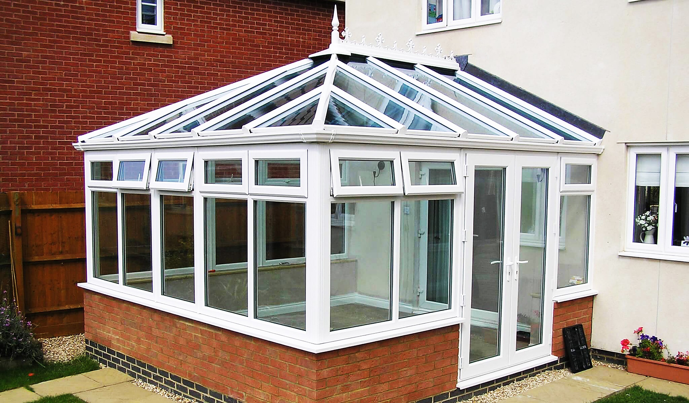 Glass conservatory with roof panels on a brick house